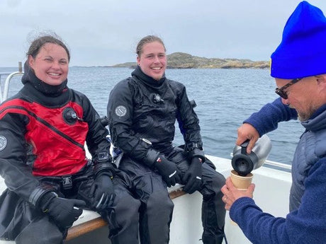 small group of happy divers sat together on a dive boat