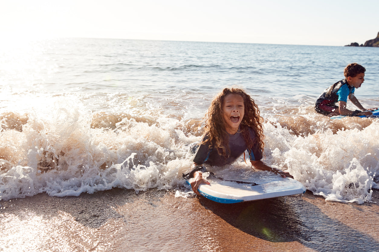 two children bodyboarding in the sea