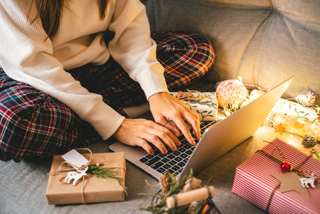 aerial shot of woman using laptop surrounded by christmas gifts